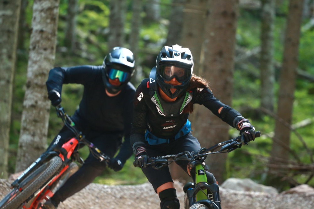 Two riders on an enduro mountain bike trail through forest